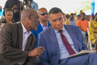 Prime Minister, the Most Hon. Andrew Holness (right), converses with National Housing Trust (NHT) Chairman, Linval Freeman, during the official handover of residential serviced lots under the new Friendship Oaks Phase 1 development in Goshen, St. Elizabeth, on May 17.