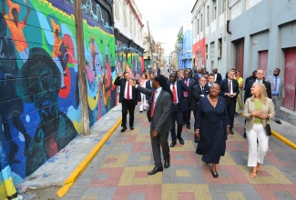 Minister of Culture, Gender, Entertainment and Sport, Hon. Olivia Grange (centre), leads members of the diplomatic corps on a tour of the downtown Kingston Artwalk district. At left, State Minister in the Ministry. Hon. Alando Terrelonge, points out murals of Reggae music icons that are painted on the walls of buildings.  The tour of the area, which took place on Wednesday, (March 1), was part of activities for Diplomatic Week from February 27 to March 3.