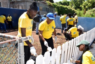 HEART/NSTA Trust volunteers paint a picket fence at Stimulation Plus Child Development Centre on Ostend Close in Kingston on Labour Day (May 23).

