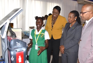 Minister of State in the Ministry of Education and Youth, Hon. Marsha Smith (second right), listens as 17-year-old Winston Jones High School student, Jodean Raymond (left), explains how her 