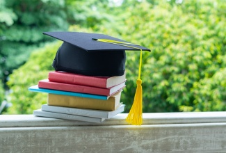 A graduation cap rests upon books, symbolizing the culmination of graduate studies. 