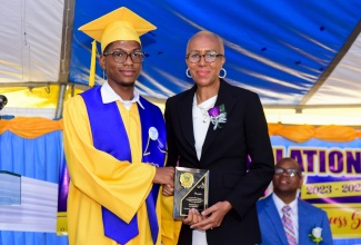 Minister of Education and Youth, Hon. Fayval Williams (right) is presented with a plaque of appreciation by student Marvin Blake (left) during the Guy’s Hill High School graduation ceremony held on the school campus in St. Catherine on Thursday (June 27).