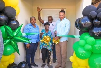 Prime Minister, the Most Hon. Andrew Holness (right), cuts the ribbon to a new house for Sonia Mitchell (centre) in Hayes, Clarendon, on May 24, which was built under the New Social Housing Programme (NSHP). Sharing in the occasion are Chairperson of the Oversight Committee, NSHP, Judith Robb Walters (left), and Member of Parliament for Clarendon South Eastern, Hon. Pearnel Charles Jr.