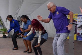 Minister of Justice, Hon. Delroy Chuck (right), demonstrates his dancing skills alongside individuals attending the Legal Aid Council justice fair for persons with disabilities, which was held at Emancipation Park in New Kingston on Friday (June 21).