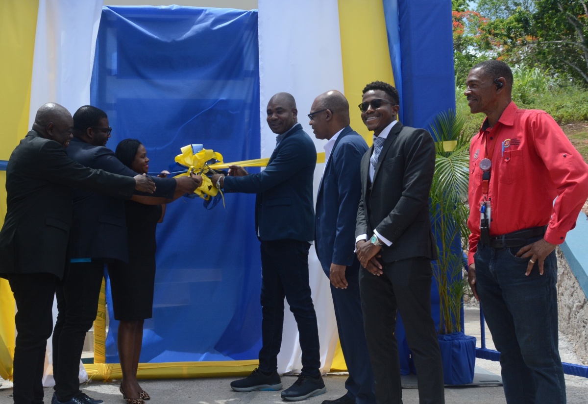 Minister of State in the Ministry of Finance and the Public Service and Member of Parliament for St. Ann South Western, Hon. Zavia Mayne (centre), cuts the ribbon to officially open a multipurpose building in Watt Town, St. Ann, on Friday (June 14). He is assisted by (from left) Deputy Mayor of St. Ann, Councillor Cardell Wickham; Executive Director Tourism Product Development Company Limited (TPDCo), Wade Mars; Director, Constituency Development Fund (CDF), Kedesha Rochester; Postmaster General, Jamaica Post, Lincoln Allen; Legal Officer and Corporate Secretary, Universal Service Fund (USF), Charles Young; and Senior Project Officer, Jamaica Bauxite Institute (JBI), Wesley Harley.