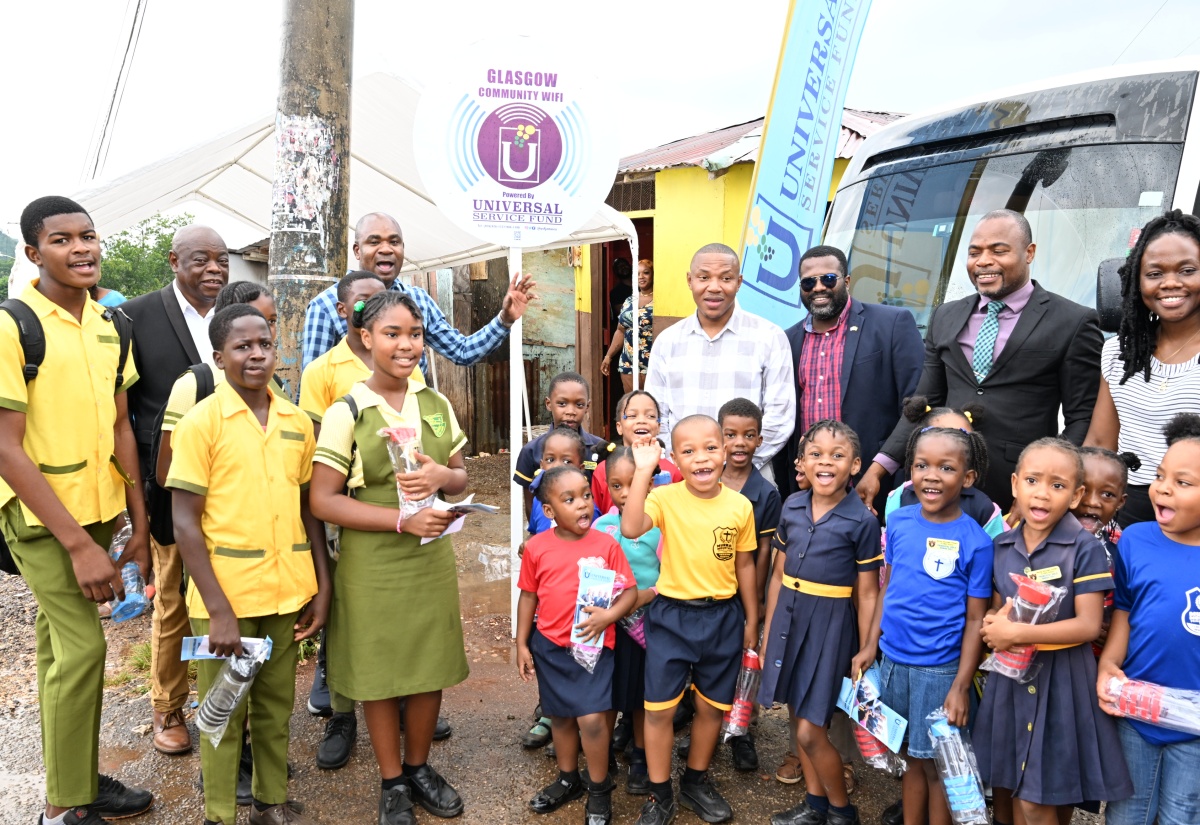 tate Minister in the Ministry of Finance and the Public Service, Hon. Zavia Mayne (background, third left), is joined by representatives from the Universal Service Fund (USF), students of Murray Mountain Primary and Infant School and Grants Mountain Primary School and other stakeholders, during the launch of Community Wi-Fi service in the Glasgow Lodge District in Murray Mountain, St. Ann, on Friday (June 21)