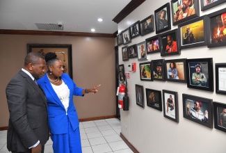 Minister of Culture, Gender, Entertainment and Sport, Hon. Olivia Grange, shows images of Jamaican artistes to Ambassador-designate of the Republic of Zimbabwe to Jamaica, Paul Chikawa, who called on the Minister at her New Kingston offices on Wednesday (June 26). 

