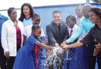 Minister Without Portfolio in the Ministry of Economic Growth and Job Creation, Senator the Hon. Matthew Samuda (centre), commissions into service the Mitchell Town Pipeline Replacement and Tank Rehabilitation Project in Clarendon South Eastern earlier this year. Among the other participants is Minister of Labour and Social Security and Member of Parliament, Hon. Pearnel Charles Jr. (second right), students of schools in the constituency and National Water Commission (NWC) representatives.  

