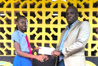 Educator and past student of Kitson Town Primary School in St. Catherine, Euton Gordon, presents a bursary to former grade-five student, Amelia Brown, during a recent ceremony held at the institution in St. Catherine.  The bursary will assist Amelia as she heads to St. Catherine High School in September after mastering the Primary Exit Profile (PEP) examinations.

