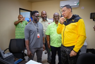 Prime Minister, the Most Hon. Andrew Holness (right), uses a two-way radio, which is part of the Disaster Emergency Communication System during a visit to the National Emergency Operations Centre, located at the Office of Disaster Preparedness and Emergency Management (ODPEM) in Kingston on Wednesday (July 3). Others (from left) are: Project Engineer at the Japan International Co-operation Agency (JICA), Dane Lawrence; Acting Director General, ODPEM, Richard Thompson, and Minister of Local Government and Community Development, Hon. Desmond McKenzie.

