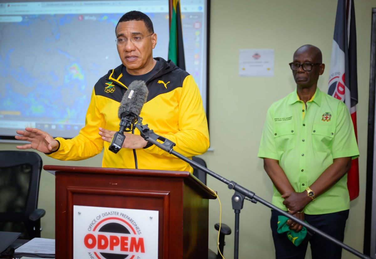 Prime Minister, the Most Hon. Andrew Holness, addresses the media during a visit to the National Emergency Operations Centre, located at the Office of Disaster Preparedness and Emergency Management (ODPEM) in Kingston, on Wednesday (July 3). In the background is Minister of Local Government and Community Development, Hon. Desmond McKenzie.