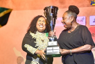 Minister of Culture, Gender, Entertainment and Sport, Hon. Olivia Grange (right), presents the Jamaica Festival Song trophy to 2024 winner, Kimiela ‘Candy’ Isaacs, during the final of the Jamaica Cultural Development Commission (JCDC) competition at Jamaica College’s Karl Hendrickson Auditorium in St. Andrew on July 13.