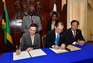 Minister of Foreign Affairs and Foreign Trade, Senator the Hon. Kamina Johnson Smith (seated, left) and Resident Representative of the Japan International Cooperation Agency (JICA), Mitsuyoshi Kawasaki (seated, centre), sign a memorandum of understanding (MOU) during the handover of emergency relief items from the Government of Japan, at Jamaica House on July 15. Looking on are Minister of Local Government and Community Development, Hon. Desmond McKenzie (standing, left); Minister without Portfolio in the Office of the Prime Minister with Oversight for Skills, Digital Transformation and Information, Senator Dr. the Hon. Dana Morris-Dixon (standing left); and Japanese Ambassador, His Excellency Yasuhiro Atsumi. The donation comes after the Category 4 Hurricane Beryl impacted Jamaica on July 3.