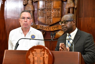 Minister of Science, Energy, Telecommunications and Transport, Hon. Daryl Vaz (left), listens as Director General of the Office of Utilities Regulation (OUR), Ansord Hewitt, addresses Wednesday