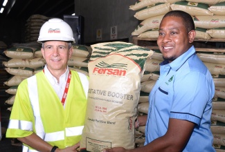 Minister of Agriculture, Fisheries and Mining, Hon. Floyd Green (right), receives a donation of granular fertiliser blend from Managing Director of Newport-Fersan (Jamaica) Limited, Dennis Valdez (left), during the Hurricane Recovery Support Ceremony on Tuesday (July 30), at the company’s Wherry Wharf Complex in Kingston.