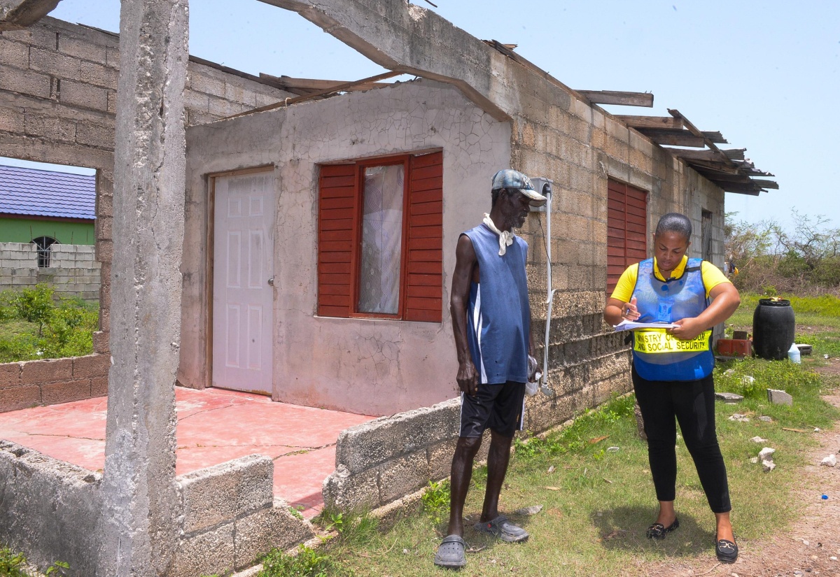 Liaison Officer at the Ministry of Labour and Social Security, Felicia Radlein, records information provided by Lionel Town resident, Adam Blake, on the extent of damages sustained from the passage of Hurricane Beryl. Occasion was a visit to the community in Clarendon on Wednesday (July 10) by teams from the Ministry to assess damages and provide relief items to affected residents.
