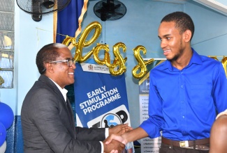 State Minister in the Ministry of Labour and Social Security, Dr. the Hon. Norman Dunn (left) greets past student of the Ministry’s Early Stimulation Programme, Joshua Hall during the staging of the programme’s 2024 graduation exercise held on July 10 at the Apostolic Church of Jamaica Bethel Temple in Kingston.

