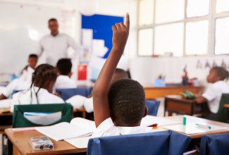 Child raising hand to answer a question in class.