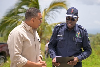 Prime Minister, the Most Hon. Andrew Holness (left), in discussion with Head of the St. Elizabeth Police Division, Superintendent Coleridge Minto, in Donegal district, St. Elizabeth, on Friday, July 19, during the handover of a housing unit under the New Social Housing Programme (NSHP).

