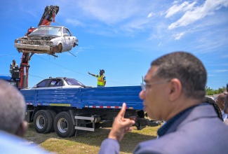 Prime Minister, the Most Hon. Andrew Holness, observes as workers from the National Solid Waste Management Authority (NSWMA) remove old motorcars under the Derelict Vehicles and Bulky Waste Removal programme. The post-Hurricane Beryl national clean-up exercise was officially launched on July 24 at the Waterford Community Centre in Portmore, St. Catherine.

