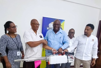 Mayor of Savanna-la-Mar, Councillor Danree Delancy (centre), hands over a fogging machine to Chief Public Health Inspector at the Westmoreland Public Health Department, Steve Morris (second left), at the Westmoreland Municipal Corporation’s offices in the parish on July 18. Sharing the moment  (from left) are Acting Medical Officer of Health for Westmoreland, Dr. Zainab Maiyaki; Accountant at the Corporation, Carolissa Simpson and Acting Chief Executive Officer at the Municipality, Marcus Bromfield. 