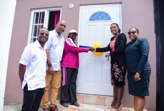 Managing Director of the HEART/NSTA Trust, Dr. Taneisha Ingleton (second right), assists homeowner Madge Shields (third left) in cutting the ribbon to her newly renovated home, at the handover ceremony on August 8 at Woodford Park in Kingston. Sharing in the moment (from left) are Councillor for the Trafalgar Division, Jesse James; Member of Parliament for St. Andrew South East, Julian Robinson; and Deputy Managing Director, HEART/NSTA Trust, Dr. Cheryl McLaughlin.

