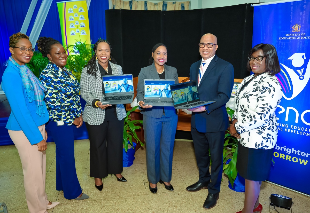 Minister of State in the Ministry of Education and Youth, Hon. Marsha Smith (third right); Permanent Secretary in the Ministry, Dr. Kasan Troupe (third left); and Chief Executive Officer, e-Learning Jamaica, Andrew Lee (second right), display some of the new laptops donated by e-Learning Jamaica to the Jamaica Library Service (JLS) at the Kingston and St. Andrew Parish Library, 2 Tom Redcam Drive, on Tuesday (August 13). Others from left are Senior Director, JLS, Kishma Simpson; Principal Director, Telecommunications, Ministry of Science, Energy, Telecommunications and Transport, Kaydian Smith Newton; and Director General, JLS, Maureen Thompson.