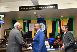 Mayor of Kingston, Councillor Andrew Swaby (centre), shakes hands with Dr. Julius Garvey, during a recent ceremony to name the Kingston and St. Andrew Municipal Corporation (KSAMC) council chamber in honour of his father and Jamaica’s first National Hero, the Right Excellent Marcus Mosiah Garvey. The official naming of the ‘Marcus Garvey Council Chamber’ took place during a special KSAMC sitting on Saturday (August 17), the anniversary date of the National Hero’s birth. Looking on is Deputy Mayor of Kingston, Senator Councillor Delroy Williams.

