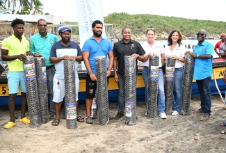 Minister of Agriculture, Fisheries and Mining, Hon. Floyd Green (fourth right), with fishers after donating rolls of mesh wire during a handover ceremony at Great Bay Fishing Beach, Treasure Beach, St. Elizabeth, on August 22. Also sharing the moment are Principal Director of Technical Services at the Rural Agricultural Development Authority (RADA), Winston Simpson (right); Operations Director at Sandals Foundation, Karen Zacca (second right); and Director of the Sandals Foundation, Heidi Clarke (third right).