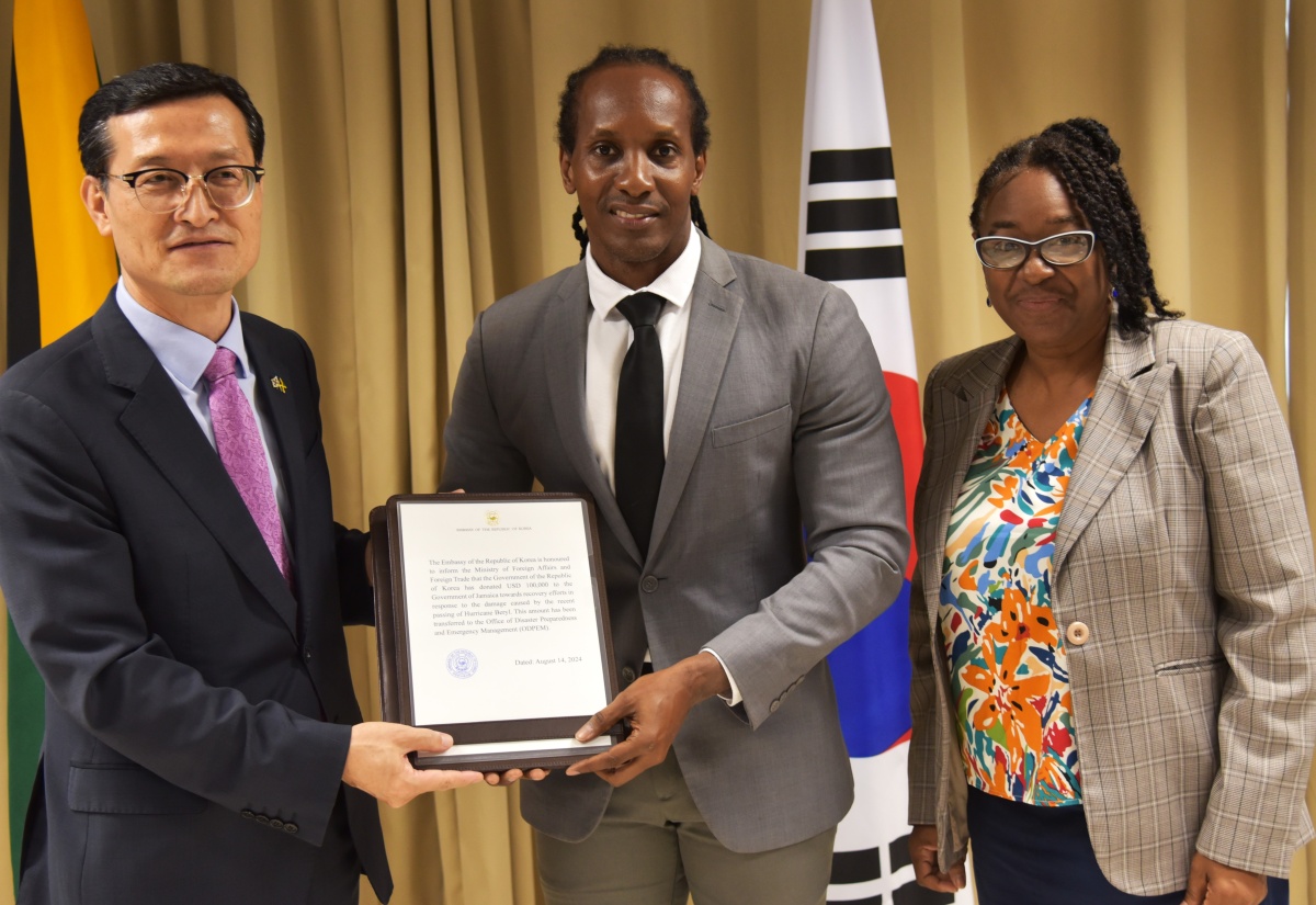 State Minister in the Ministry of Foreign Affairs and Foreign Trade, Hon. Alando Terrelonge (centre), accepts a formal confirmation of a US$100,000 donation from Charge d’Affaires, Embassy of the Republic of Korea to Jamaica, Jin-wook Kim (left), at the downtown Kingston offices of the Ministry on Wednesday (August 14). Looking on at right is Acting Deputy Director General of the Office of Disaster Preparedness and Emergency Management (ODPEM), Michelle Edwards.