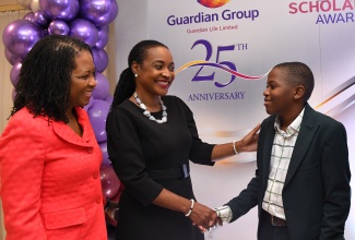 State Minister in the Ministry of Education and Youth, Hon. Marsha Smith (centre), and President of Guardian Life Limited, Meghon Miller Brown (left), share a light moment with the 2024 top Primary Exit Profile (PEP) boy, Aiden Cummings, during Friday’s (August 23) Guardian Group Scholarship & Grant Awards Ceremony 2024, at The Jamaica Pegasus hotel in New Kingston.