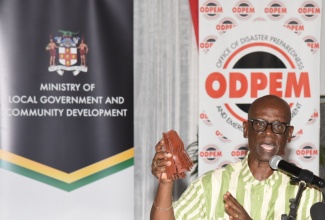 Minister of Local Government and Community Development, Hon. Desmond McKenzie, displays hurricane roof straps while addressing a ceremony on August 26, at the Hugh Lawson Shearer Community Centre in Rocky Point, Clarendon, where the Government commenced its distribution of 10,000 of the straps.

