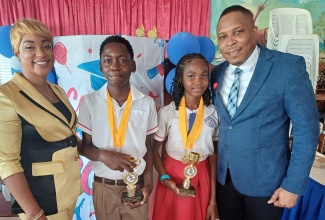Principal of the St. Catherine-based Waterford Primary School, Nicola Francis-Grizzle (left), and Chairman of the school, Marsden Dennis (right), with two of their top students at the recent graduation, held at the Hope Temple Pentecostal Church of God in the community. The students are (from second left) Kesneil Brown, and Andrea Dias.

