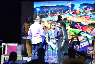 Minister of Culture, Gender, Entertainment and Sport, Hon. Olivia Grange (right), embraces Kate Thomas (second right), after Ms. Thomas and her sister, Aidee Walker (second left), apologised to the people of Jamaica for the involvement of their ancestors, the Clan Malcolm of Argyll, in slavery in Jamaica. Occasion was the Seville Emancipation Jubilee, held at the Seville Heritage Park in St. Ann from July 31 to Emancipation Day, August 1. At left is Mayor of St. Ann's Bay, Councillor Michael Belnavis. 

