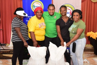 Minister of Agriculture, Fisheries and Mining, Hon. Floyd Green (centre), hands over fertilisers to Buff Bay Valley coffee farmers during a presentation ceremony at the Bangor Ridge Church of God of Prophecy on September 11. The farmers are (from left) Orlando Willis, Norma Howard, Shernette Cobran, and Teneshia Bender.