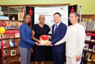 Minister of Education and Youth, Hon. Fayval Williams (second left), is presented with a gift by Ambassador of the People’s Republic of China to Jamaica, His Excellency Chen Daojiang (second right), during the recent Chinese Collection Handover Ceremony at the Kingston and St. Andrew Parish Library. Sharing the moment (from left) are Senior Director, Jamaica Library Service, Kishma Simpson, and Chinese Director of the Confucius Institute at the University of the West Indues (UWI), Lei Feng.