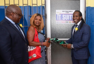 Minister of State in the Ministry of Foreign Affairs and Foreign Trade, Hon. Alando Terrelonge (right), assists Founder of the Angel Foundation, Angelia Christian, with cutting the ribbon for the official opening of an AutoCAD room at the Greater Portmore High School in St. Catherine, on September 18. Sharing the moment is Principal of the school, Ricardo Ross.