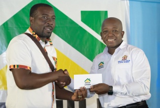 Minister of Labour and Social Security, Hon. Pearnel Charles Jr. (right), presents a cheque to ‘Rebuild Jamaica’ beneficiary, Kemar Evans, during a handover ceremony at the Anglican Church Hall in Port Maria, St. Mary, on September 6.