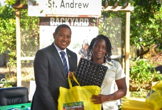 Minister of Agriculture, Fisheries and Mining, Hon. Floyd Green (left), presents a backyard gardening kit to Corporate Area resident Arlene Nelson, at the Rural Agricultural Development Authority (RADA) St. Andrew Parish Office in December 2023.