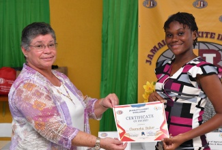 General Manager at the Jamaica Bauxite Institute (JBI), Yolanda Drakapoulos (left), presents a scholarship certificate to Chameka Baker, one of 14 tertiary-level scholars, who have benefitted under the JBI Hoilett/Lambert Scholarship. The presentation was made at the official launch of the scholarship at the JBI’s Hope Gardens location in St. Andrew on Friday (Sept. 13).