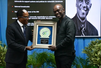 Minister of State in the Ministry of Labour and Social Security, Dr. the Hon. Norman Dunn (left) presents the award for Distinguished Senior Citizen to broadcaster and lecturer, Dr. Orville Taylor. Occasion was the National Council for Senior Citizens (NCSC) regional awards ceremony held at the Cardiff Hotel and Spa in Runaway Bay, St. Ann, on Friday (September 27).