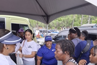 Executive Director, Jamaica Vacations (JAMVAC), Joy Roberts (left), looks on as school supplies are presented to craft traders in Ocho Rios, St. Ann, for their children as part of an assistance initiative spearheaded recently by the Ministry of Tourism and other relevant agencies. The event was held at Ocho Rios Primary School.