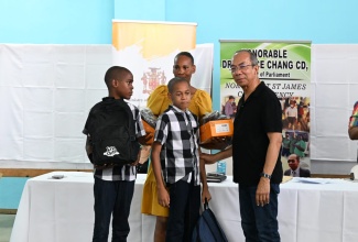 Deputy Prime Minister and Minister of National Security, Hon Dr. Horace Chang (right), participates in a recent handover of back-to-school supplies to students at the Flanker Community Centre in Montego Bay, St. James.

