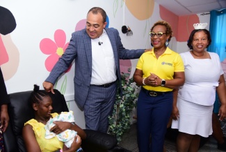 Health and Wellness Minister, Dr. the Hon. Christopher Tufton (second left), looks on as new mother, Natalia Marage, cradles her infant son, Rashawn. The occasion was the official handover of the newly refurbished breastfeeding room in the nursery at the Victoria Jubilee Hospital in Kingston, by the Kiwanis Club of New Kingston on Tuesday (October 15). Others sharing the moment are President of the Kiwanis Club of New Kingston, Sophia Bernard-Fairman (second right); and Nurse Manager of the Victoria Jubilee Neonatal Intensive Care Unit (NICU), Keisha Brown.

