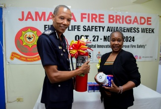 Jamaica Fire Brigade (JFB) Commissioner,  Stewart Beckford, presents fire-safety devices to Interim Director of the Jamaica National Children’s Home in St. Andrew, Claudette White. The presentation was made at the Home on Wednesday (October 29) as part of activities marking Fire and Life Safety Awareness Week from October 27 to November 2 under the theme ‘Embracing Digital Innovation to Improve Fire Safety’.

