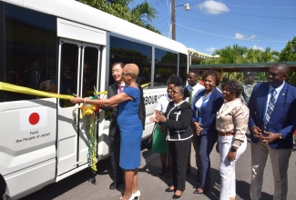 Minister of Education and Youth, Hon. Fayval Williams, and Ambassador of Japan to Jamaica, His Excellency Yasuhiro Atsumi, cut the ribbon for the handover of a 29-seater bus, donated by the Japanese Government to the Old Harbour High School in St. Catherine, on October 4. Observing are Custos of St. Catherine, Hon. Icylin M. Golding, who is also Chairman of the school (fourth right, foreground), students and other officials.

