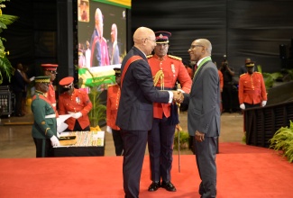 Governor-General, His Excellency the Most Hon. Sir Patrick Allen (left), presents the Order of Distinction in the Rank of Commander (CD) to Courney Campbell, at the recent Ceremony of Investiture and Presentation of National Honours and Awards, held at the National Indoor Sports Centre in St. Andrew.

