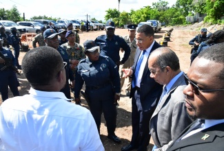 Prime Minister, Dr. the Most Hon. Andrew Holness (third right), speaks with Commanding Officer for the Jamaica Constabulary Force (JCF) Kingston Eastern Division, Superintendent Tomielee Chambers (fourth right), and other members of the security forces, during his visit to Pleasant Heights in Rockfort, Kingston, on Tuesday (October 22), in the aftermath of a mass shooting at a football match in the community on National Heroes Day, Monday, October 21. Among the officials accompanying Dr. Holness are Deputy Prime Minister and National Security Minister, Hon. Dr. Horace Chang (second right), and Minister Without Portfolio in the Ministry of Economic Growth and Job Creation with Responsibility for Works, Hon. Robert Morgan (right).

