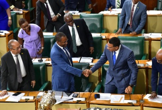 Prime Minister, Dr. the Most Hon. Andrew Holness (right), shakes hands with outgoing Minister of Finance and the Public Service, Dr. the Hon. Nigel Clarke, in the House of Representatives on Tuesday (October 29), while other members of the House bang their desks in respect.

