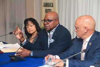 Minister of Tourism, Hon. Edmund Bartlett (centre) is flanked by the President of the Jamaica Hotel and Tourist Association (JHTA), Robin Russell (right), and JHTA Executive Director, Camille Needham (left) as he responds to questions from JHTA members following his presentation at their 63rd Annual General Meeting held yesterday (October 12) at the Jamaica Pegasus Hotel.